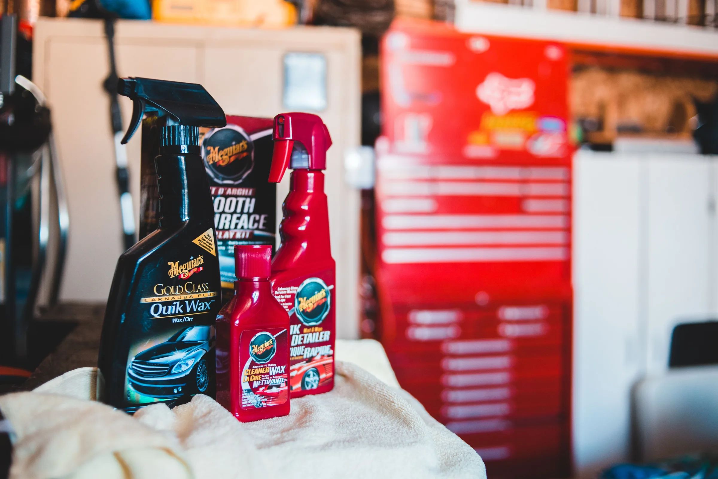 Car cleaning products and a microfiber cloth on a garage workbench