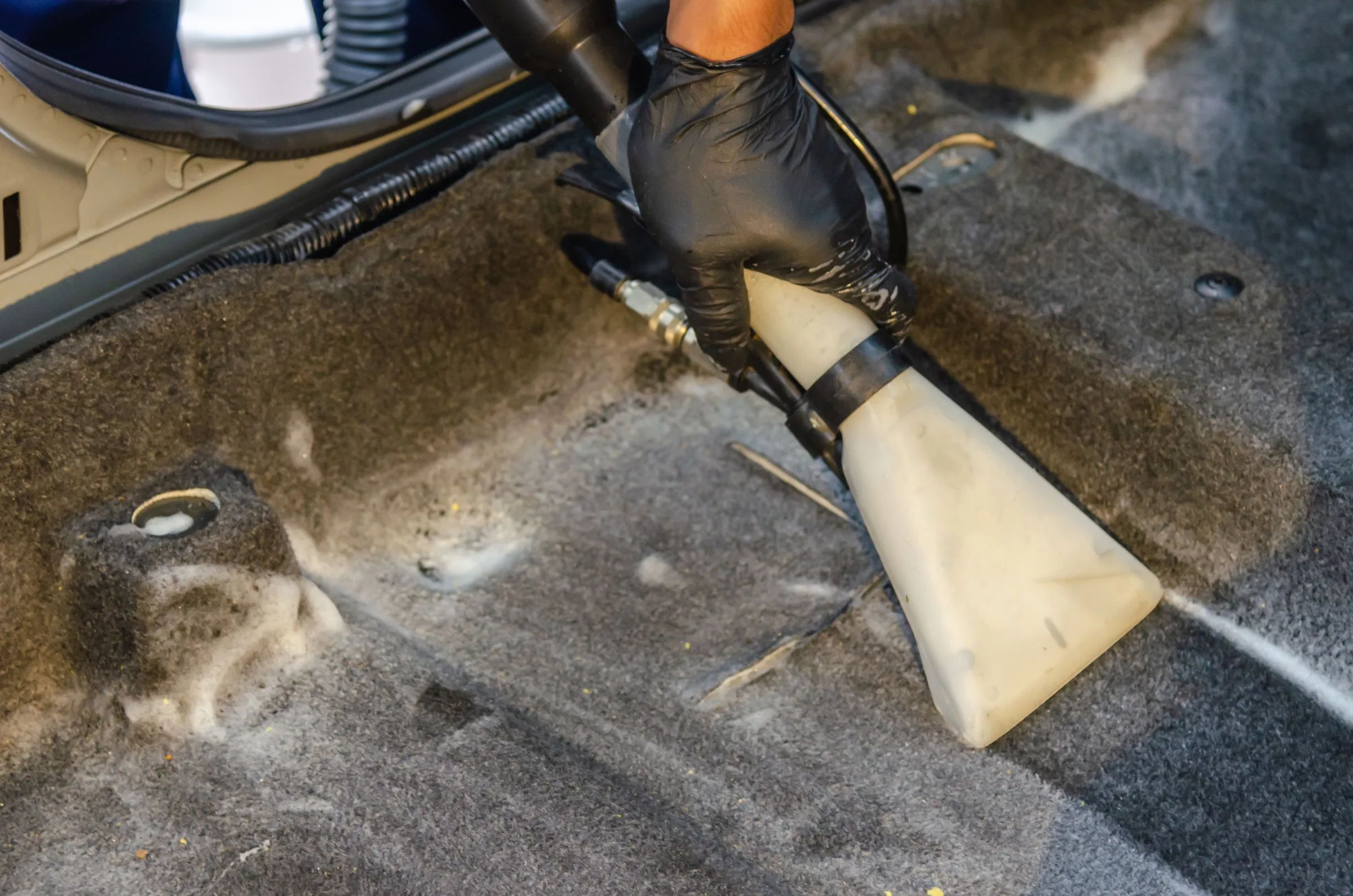A carpet extractor cleaning the bare floor carpet of a car